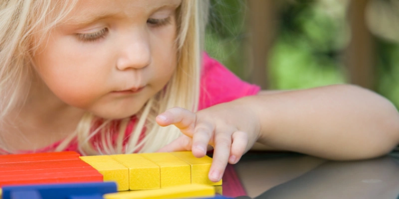 Childcare Learning Stories - Young Girl Playing with Blocks